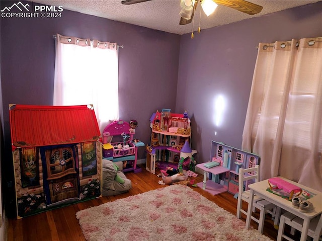 playroom with ceiling fan, hardwood / wood-style floors, and a textured ceiling