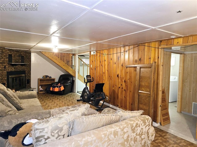 living room featuring washer / clothes dryer, wood walls, and a fireplace