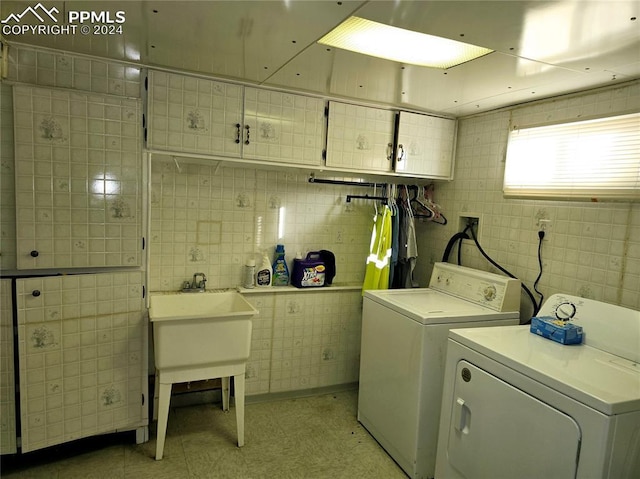 laundry area with washer and clothes dryer, cabinets, and tile walls