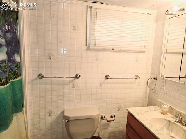 bathroom with curtained shower, vanity, tile walls, and toilet