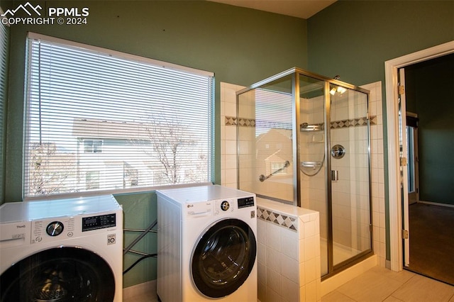 clothes washing area with washer and clothes dryer, light tile patterned flooring, and a healthy amount of sunlight