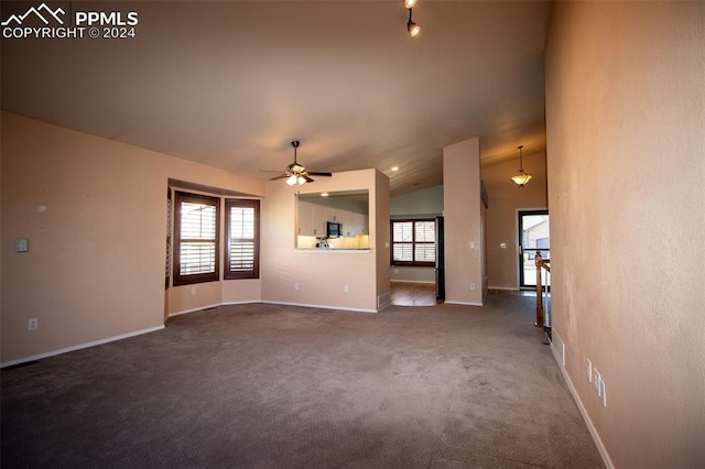 unfurnished living room featuring ceiling fan, vaulted ceiling, and dark colored carpet