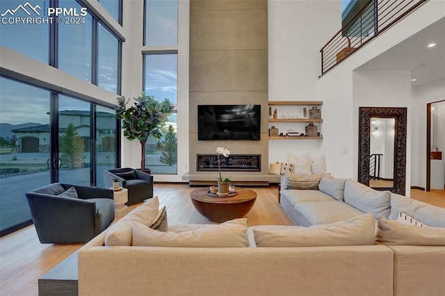 living room featuring hardwood / wood-style floors, a towering ceiling, and a fireplace