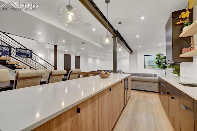 kitchen with wine cooler, light hardwood / wood-style flooring, and hanging light fixtures