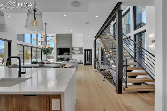 kitchen featuring pendant lighting, light hardwood / wood-style floors, light stone countertops, and a towering ceiling