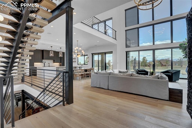 living room with a chandelier, a high ceiling, light wood-type flooring, and sink