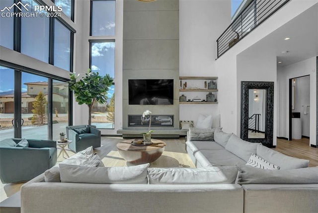 living room featuring hardwood / wood-style flooring, a fireplace, and a high ceiling