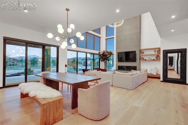 dining room featuring a mountain view, a towering ceiling, light hardwood / wood-style floors, and an inviting chandelier