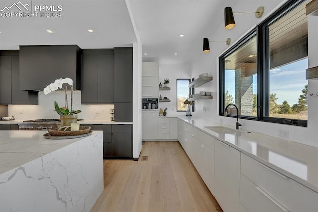 kitchen featuring light stone countertops, sink, white cabinets, and light hardwood / wood-style floors