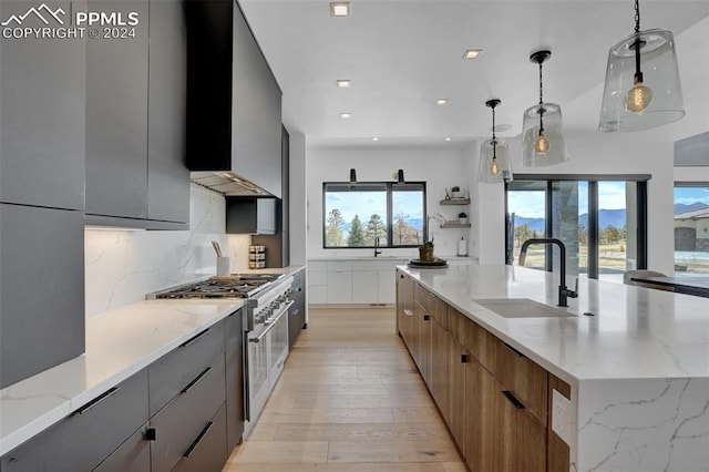 kitchen featuring high end stove, decorative light fixtures, plenty of natural light, and sink