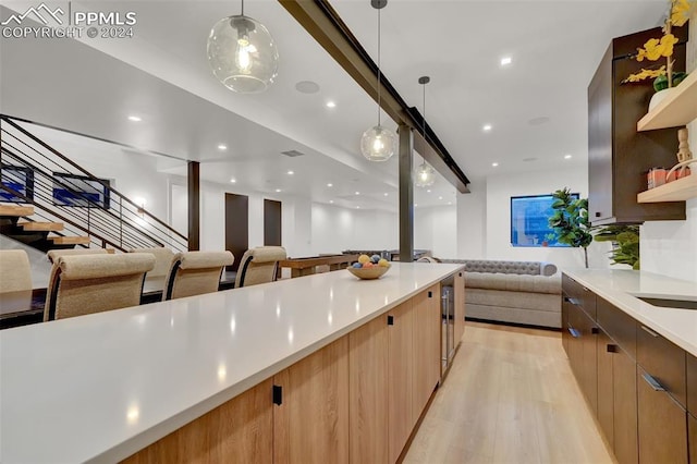 kitchen with light hardwood / wood-style floors, hanging light fixtures, and wine cooler