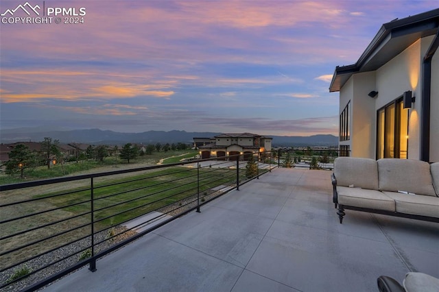 patio terrace at dusk with a mountain view, a balcony, and an outdoor hangout area