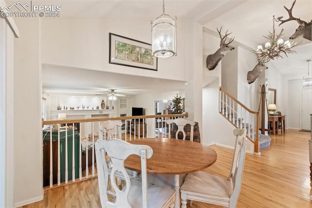 dining area featuring ceiling fan with notable chandelier, light wood-type flooring, and vaulted ceiling