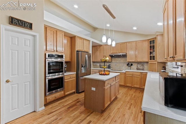 kitchen featuring a center island, lofted ceiling, light wood-type flooring, decorative light fixtures, and stainless steel appliances