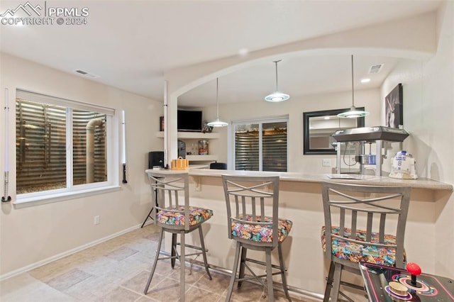 kitchen with kitchen peninsula, a breakfast bar, and pendant lighting