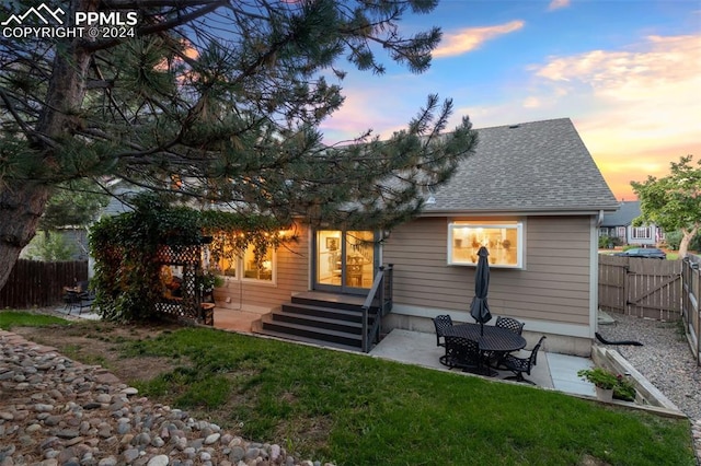 back house at dusk with a yard and a patio