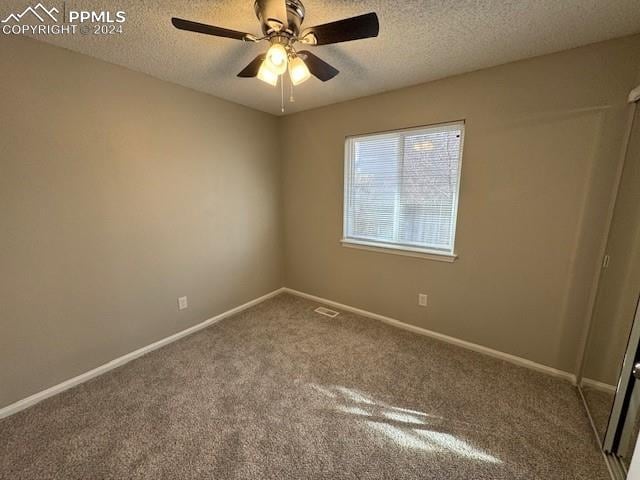 carpeted empty room with ceiling fan and a textured ceiling