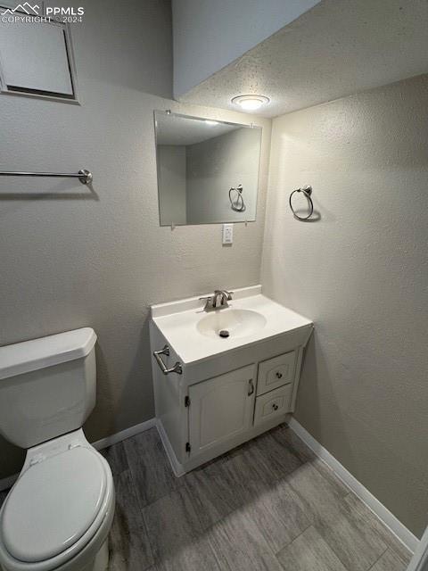 bathroom with a textured ceiling, vanity, and toilet