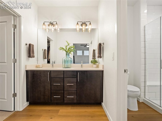 bathroom featuring ceiling fan, hardwood / wood-style floors, toilet, a shower with door, and vanity