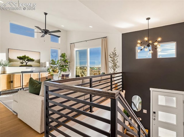 interior space with hardwood / wood-style floors, ceiling fan with notable chandelier, and high vaulted ceiling