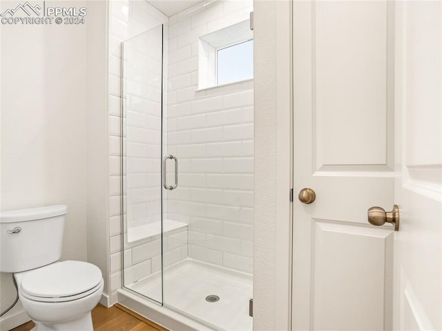 bathroom featuring walk in shower, hardwood / wood-style flooring, and toilet