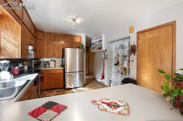 kitchen with appliances with stainless steel finishes, kitchen peninsula, sink, and decorative backsplash