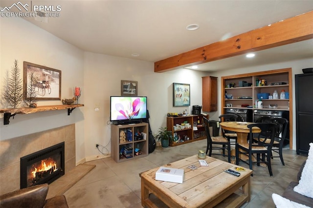 living room with beam ceiling, separate washer and dryer, and a tile fireplace