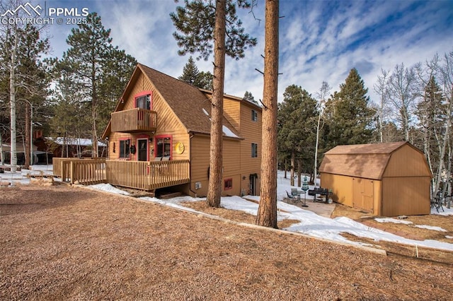 snow covered property featuring a shed and a deck