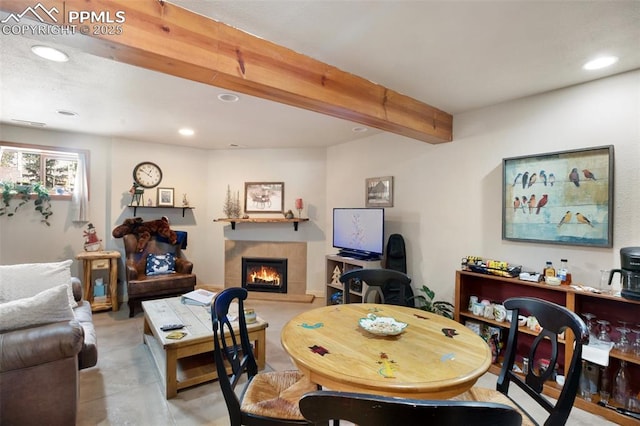 dining area featuring a tiled fireplace and beam ceiling