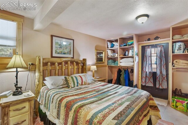 bedroom with beam ceiling, a textured ceiling, and a closet