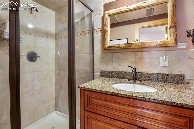 bathroom with an enclosed shower, vanity, and backsplash