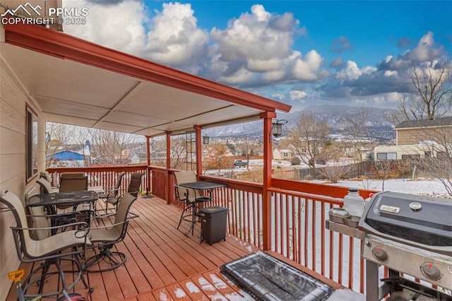 snow covered deck with a grill and a mountain view