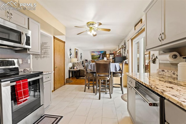 kitchen featuring light stone counters, appliances with stainless steel finishes, and ceiling fan