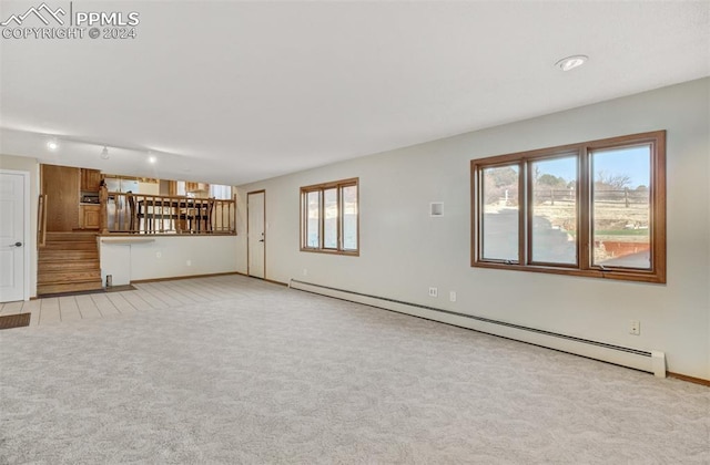 unfurnished living room featuring light colored carpet and a baseboard heating unit