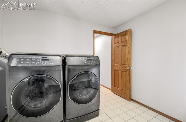 clothes washing area featuring light tile patterned floors, washer and dryer, and a textured ceiling