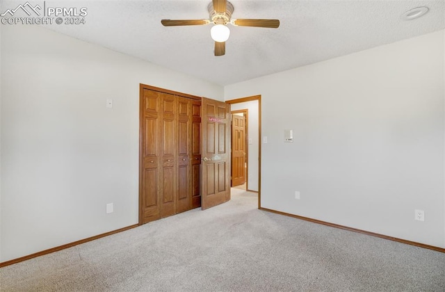 unfurnished bedroom featuring ceiling fan, a closet, and light colored carpet