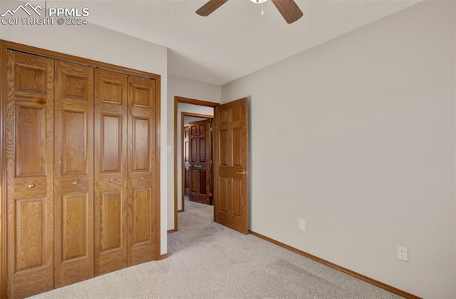 unfurnished bedroom with a closet, light colored carpet, and ceiling fan