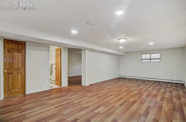 basement with a baseboard heating unit and light wood-type flooring