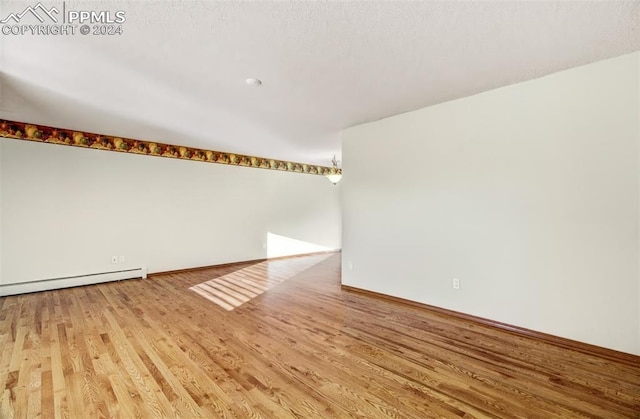 empty room featuring light hardwood / wood-style floors and a baseboard radiator