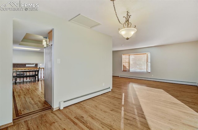 unfurnished room featuring wood-type flooring, a tray ceiling, and a baseboard heating unit