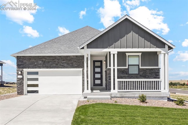 view of front of home with a front lawn, covered porch, and a garage