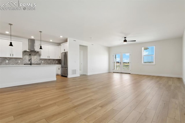 unfurnished living room with ceiling fan, light hardwood / wood-style floors, and sink