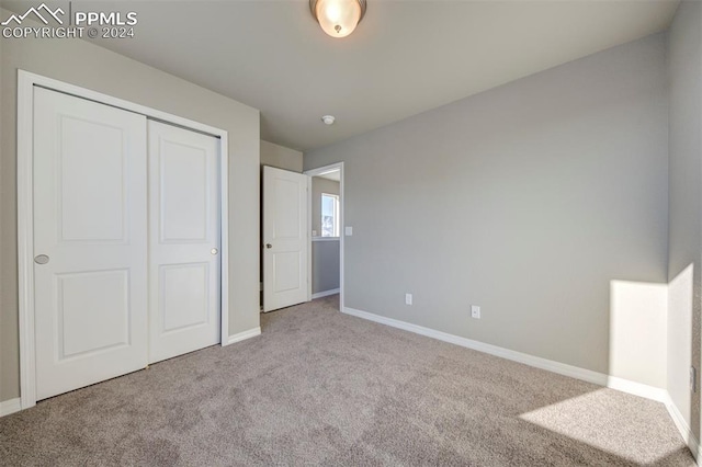 unfurnished bedroom with light carpet and a closet