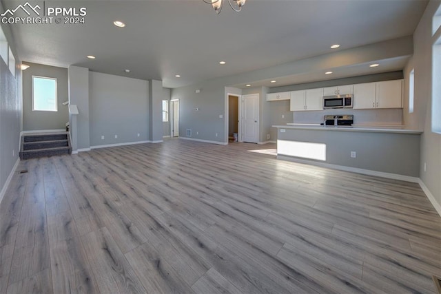 unfurnished living room featuring light hardwood / wood-style flooring and a notable chandelier