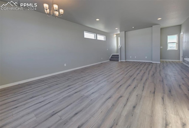 unfurnished room featuring a chandelier and light wood-type flooring