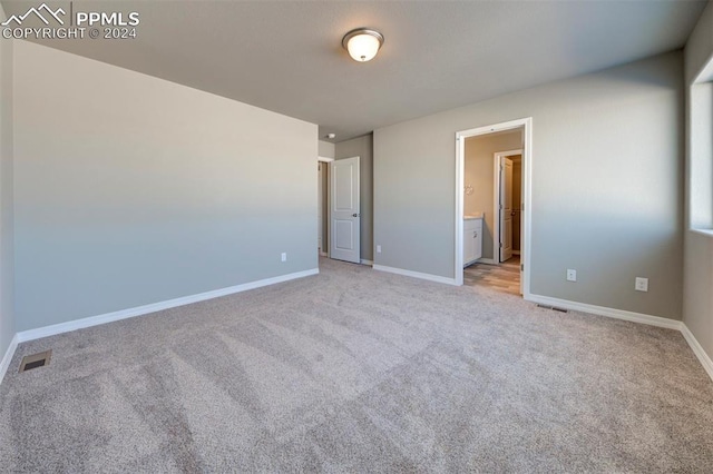 unfurnished bedroom featuring connected bathroom and light colored carpet