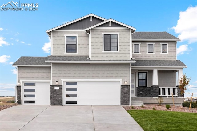 view of front of home featuring a porch, a garage, and a front lawn