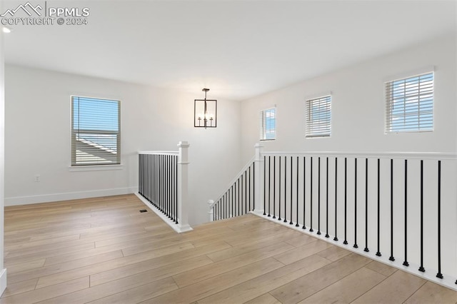 staircase featuring wood-type flooring and an inviting chandelier