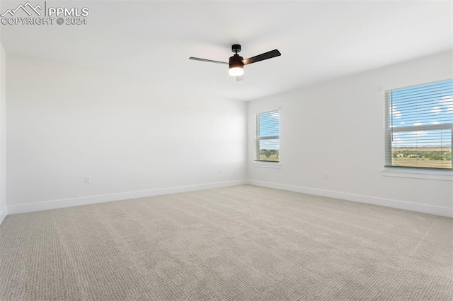 carpeted spare room featuring a wealth of natural light and ceiling fan