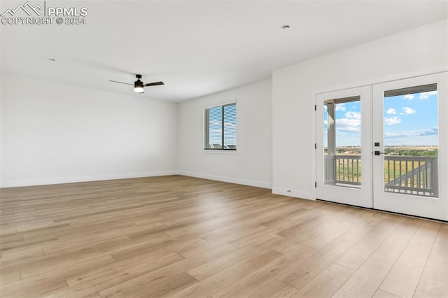 empty room with ceiling fan, light hardwood / wood-style floors, and french doors